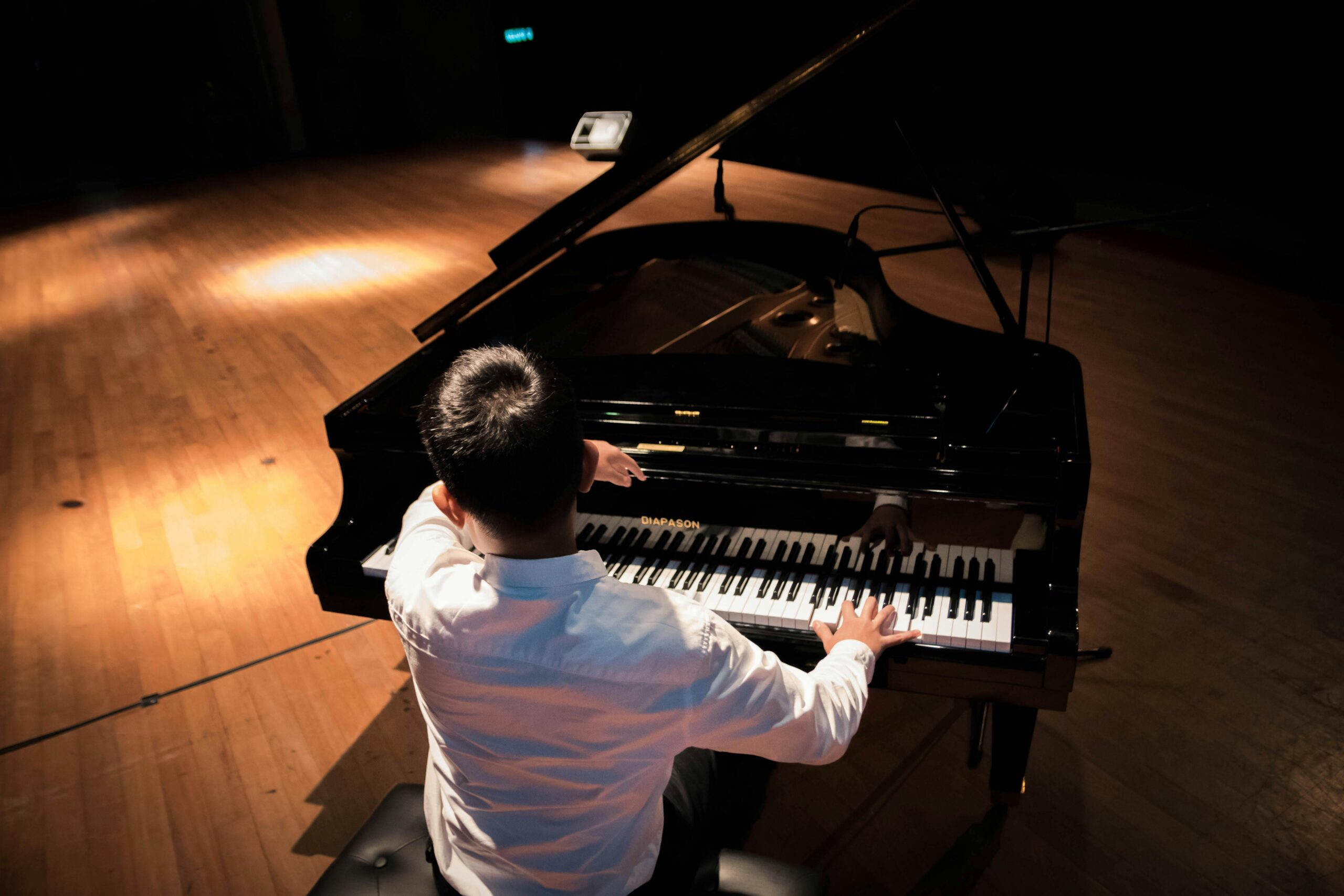 Man playing a grand piano on stage, creating musical harmony in a concert setting.